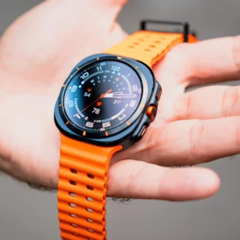 Montre connectée noire et orange affichant des données sur une main.