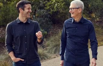 Deux hommes souriants, dont Tim Cook, marchant ensemble en extérieur.