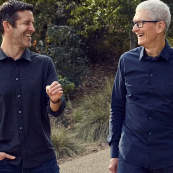 Deux hommes souriants, dont Tim Cook, marchant ensemble en ext&eacute;rieur.
