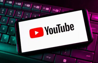 Logo YouTube sur smartphone pos&eacute; sur clavier d'ordinateur r&eacute;tro&eacute;clair&eacute;.